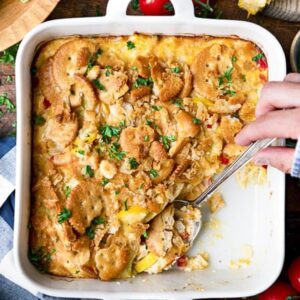 A white casserole dish with a yellow squash casserole in it. Topped with Ritz Crackers. Photo credit to A Seasoned Mom Blog.